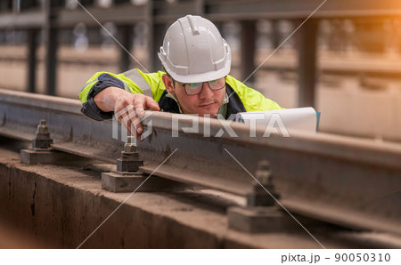 Engineer railway under  checking construction process train testing and checking railway work on railroad station with radio communication .Engineer wearing safety uniform and safety helmet in work. 90050310