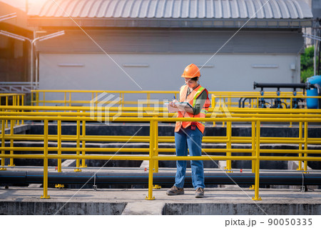 Worker wearing safety uniform under checking the waste water treatment pond industry ,she used radio communication to connect with another worker in large to control water support industry. Worker wearing safety uniform under checking the waste water treatment pond industry ,she used radio communication to connect with another worker in large to control water support industry. 90050335