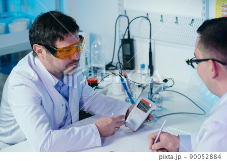 Portrait of a scientist working in the lab examines a test tube with liquid. 90052884