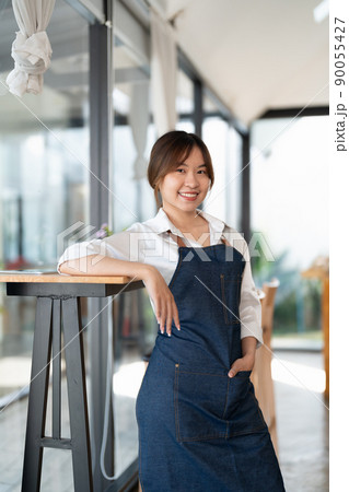 Portrait of woman barista startup successful small Asian business owner in coffee shop.Asian woman barista cafe owner. SME entrepreneur seller business concept Portrait of woman barista startup successful small Asian business owner in coffee shop.Asian woman barista cafe owner. SME entrepreneur seller business concept 90055427