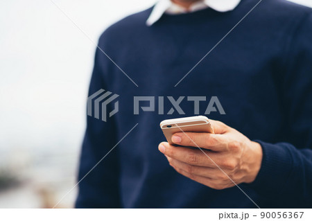 Young man wear plaid shirt.  close up hand using on cell phone during rest on sofa. sitting in watching message on mobile smart phone during break relax. soft focus. 90056367