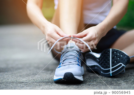 Running shoes. close up female athlete tying laces for jogging on road. Runner ties getting ready for training. Sport lifestyle. copy space banner. 90056945