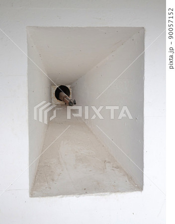 Small hole with a gun sticking out of it at the entrance of an old WW2 bunker 90057152