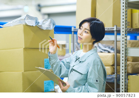 荷物を確認する作業着の棚卸中の女性作業員 荷物を確認する作業着の棚卸中の女性作業員 90057823