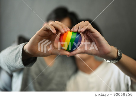 Rainbow heart shape in homosexual couple hands. LGBT, pride, relationships and equality concept Rainbow heart shape in homosexual couple hands. LGBT, pride, relationships and equality concept 90059256