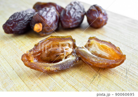 Organic fresh nutritious dried hurma dates medjool grains, on cutting board 90060695