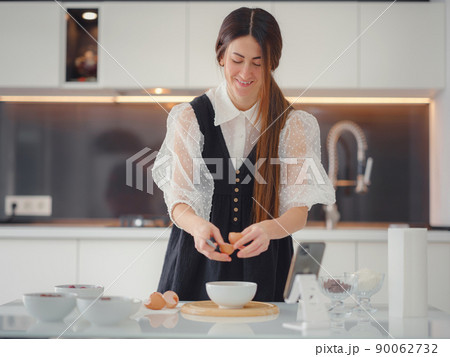 Beautiful young woman smiling while baking in kitchen at home Beautiful young woman smiling while baking in kitchen at home 90062732