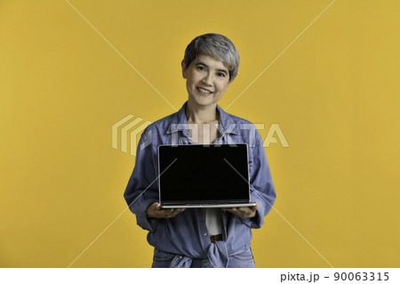 Portrait of middle aged Asian woman holding laptop computer 90063315