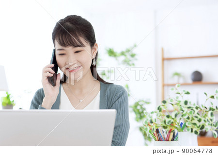 電話をしながらパソコンを操作する女性 90064778