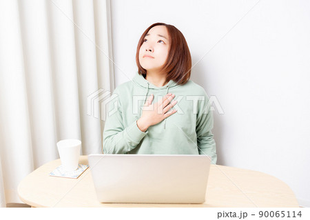 パソコンの前で胸に手を当てている女性 90065114