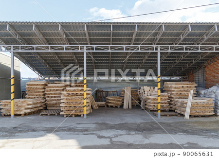 Storage and production of wooden stick cuttings for garden tools. Warehouse of household goods under a canopy on pallets. Handle for shovel and household equipment 90065631