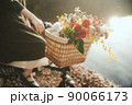 自転車のカゴいっぱいに花を入れて乗る女性 90066173