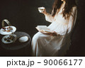 紅茶を飲みながら読書をするドレスを着た女性 90066177
