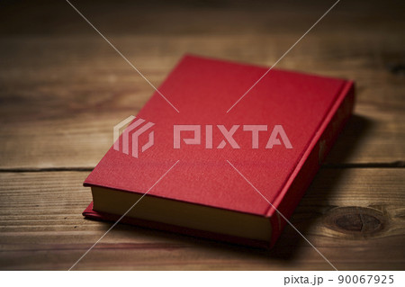古い机に置かれた赤い表紙の本 90067925