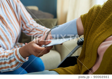 Close-up of nurse checking blood pressure of senior patient during visit to home Close-up of nurse checking blood pressure of senior patient during visit to home 90068981