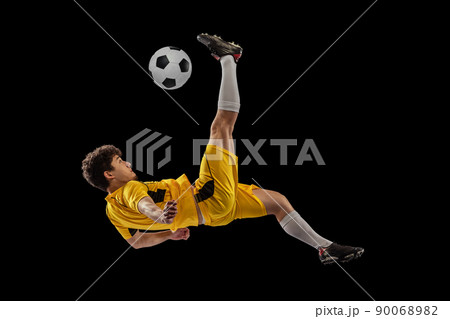 Dynamic portrait of professional football, soccer player training with ball isolated on dark background. Concept of sport, match, active lifestyle, goal and hobby Dynamic portrait of professional football, soccer player training with ball isolated on dark background. Concept of sport, match, active lifestyle, goal and hobby 90068982