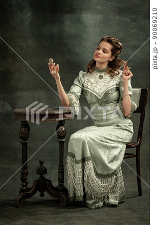 Emotional young beautiful girl, actress in image of medieval person posing isolated on dark background. Comparison of eras concept, flemish style. Art, beauty 90069210