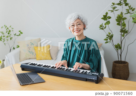 リビングでキーボードを弾くグレイヘアの女性 90071560