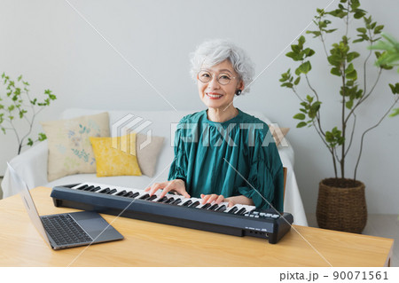 リビングでキーボードを弾くグレイヘアの女性 90071561