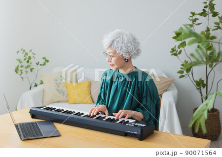 リビングでキーボードを弾くグレイヘアの女性 90071564