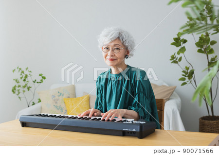 リビングでキーボードを弾くグレイヘアの女性 90071566