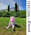 Little girl sitting on green grass turning her head back on wood background 90072632