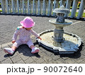 Little charming girl in a pink panama at the fountain with coins in summer 90072640