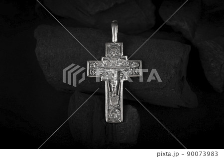 Silver crucifix necklace cross on pieces of coal. Silver crucifix necklace cross on pieces of coal. 90073983