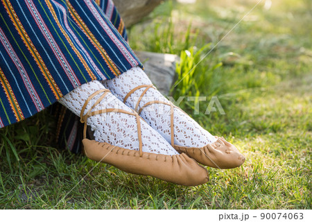 Leather bast shoes of a Latvian woman in traditional clothing. Preparing Ligo festival. Riga. Latvia 90074063