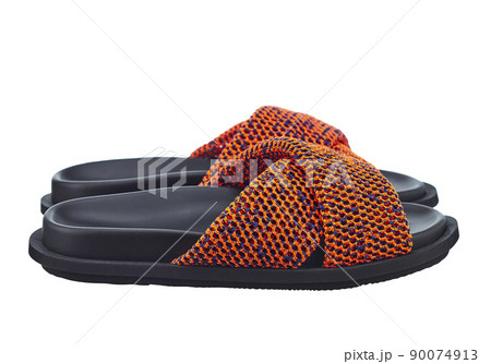Beautiful pair of high-quality sandals with a bright orange brained top and a black leather sole, isolated on a white background. Side view. Comfortable shoes for beach holidays and summer walks. Beautiful pair of high-quality sandals with a bright orange brained top and a black leather sole, isolated on a white background. Side view. Comfortable shoes for beach holidays and summer walks. 90074913