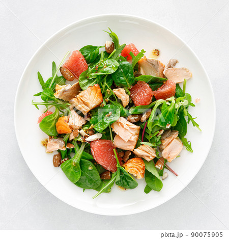 Grilled salmon salad with grapefruit, almonds and salad mix. Top view 90075905