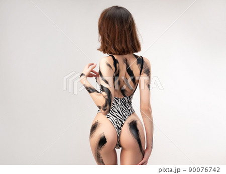 sexy girl in a spotted bodysuit swimsuit, black smears of black paint on her body 90076742