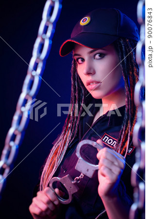 a girl in a police uniform with dreadlocks in neon light with chains and handcuffs English translation the police a girl in a police uniform with dreadlocks in neon light with chains and handcuffs English translation the police 90076843