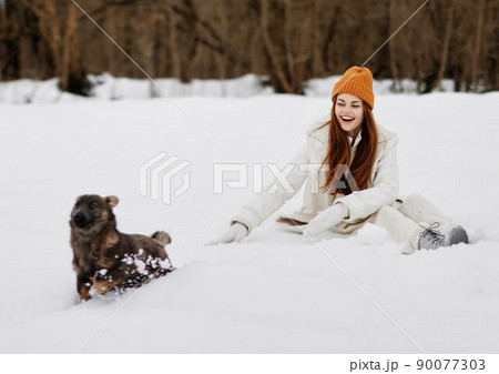portrait of a woman outdoors in a field in winter walking with a dog Lifestyle 90077303