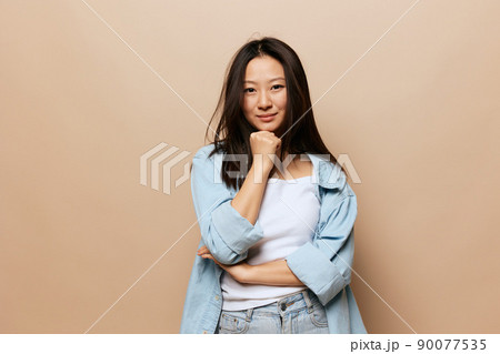Cute smiling thoughtful tanned adorable young Asian lady reclines on hand fist posing isolated on beige pastel background. People and Emotions concept. Copy Space Offer Banner. 90077535