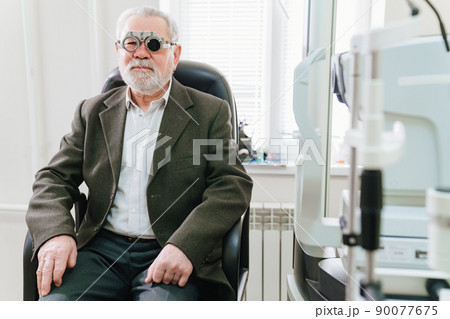making a selection of lenses, diagnosing a elderly man's vision. 90077675
