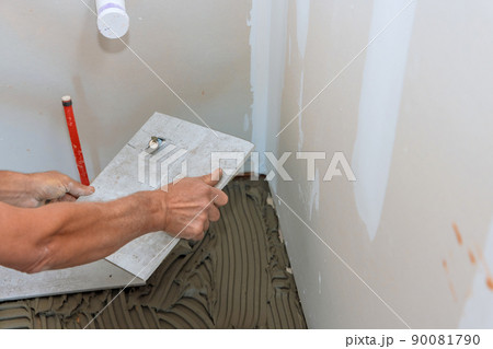 Bathroom renovation worker puts ceramic tiles on the construction site 90081790