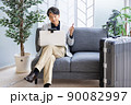 出張中に外出先のソファでリモートワークをするビジネスマン 90082997