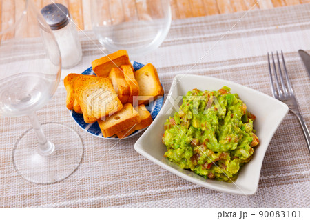 Guacamole with dry bread served on plate in restaurant 90083101