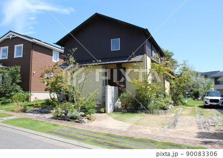 青空に映える薄い黄色い塗り壁と黒いストライプの金属板がおしゃれなスタイリッシュでモダンな邸宅 90083306