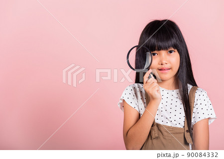 Asian little kid 10 years old funny looking through magnifying glass 90084332