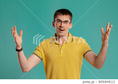 Handsome guy in a yellow casual t-shirt is posing over a blue background. Handsome guy in a yellow casual t-shirt is posing over a blue background. 90084612
