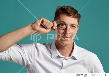 Young man in a classic white shirt is posing over a blue background. 90085221