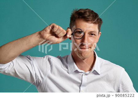 Young man in a classic white shirt is posing over a blue background. 90085222