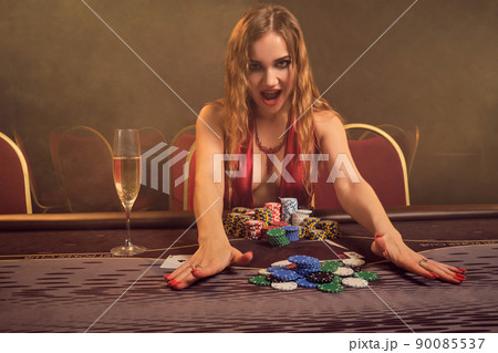 Charming woman with a beautiful hairstyle and perfect make-up is playing poker. Casino. 90085537