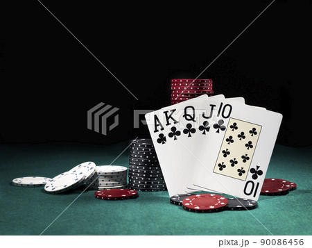 Winning combination in poker standing leaning on multicolored chips piles on green cover of playing table. Black background. Close-up. Winning combination in poker standing leaning on multicolored chips piles on green cover of playing table. Black background. Close-up. 90086456