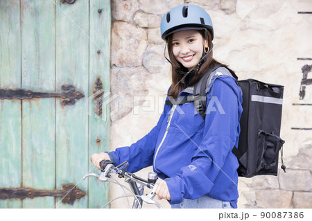 フードデリバリーイメージ　自転車でデリバリーする若い女性 90087386