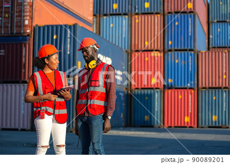 Two African american male and female engineer talking and checking loading Containers box from Cargo freight ship for import export. shipping in docks. Two African american male and female engineer talking and checking loading Containers box from Cargo freight ship for import export. shipping in docks. 90089201