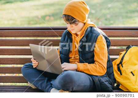 Child boy with headphones studying at home with laptop Child boy with headphones studying at home with laptop 90090701