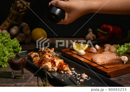 Chef is sprinkling ground pepper on grilled chicken. Barbecue, food, party concept 90093255